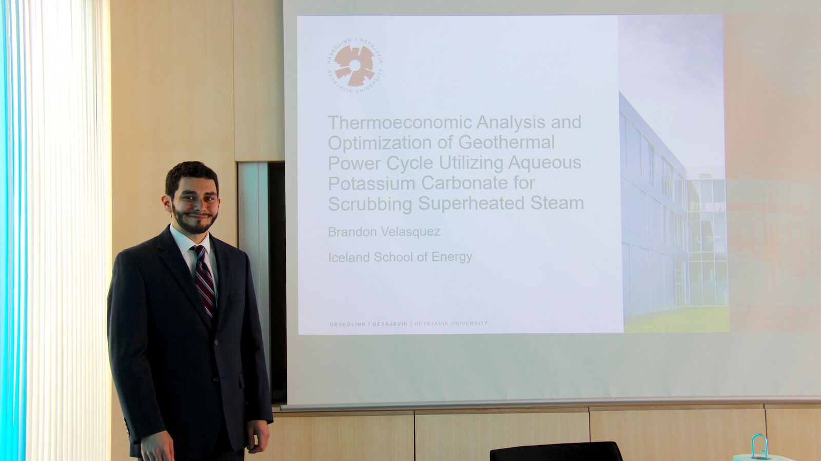 Brandon Velasquez smiling in front of his presentation title page before his thesis defence.