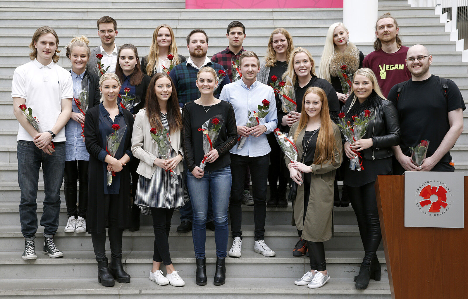 Students stand with roses in the steps in the sun